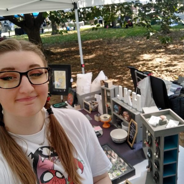 Joscelyn standing in front of the JKH Artwork booth at Art In The Park 2024