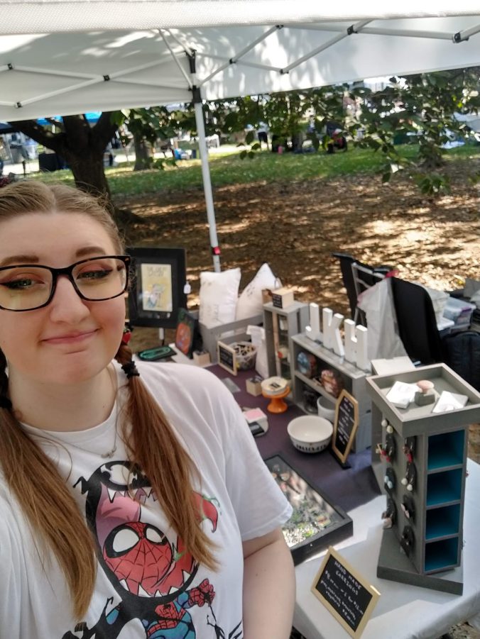 Joscelyn standing in front of the JKH Artwork booth at Art In The Park 2024